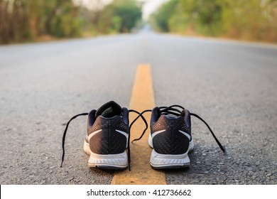 Close Up New Black Running Shoes On Asphalt Road In Morning Time