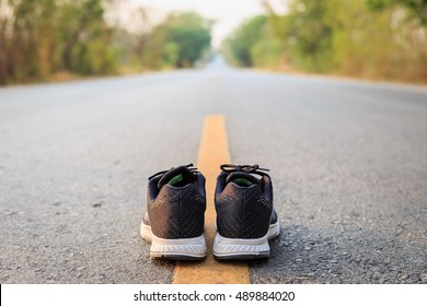 Close Up New Black Running Shoes On Asphalt Road In Morning Time