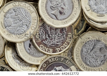 Close up of new British pound coins. Untidy pile of the new coins introduced in March 2017 that have several new security features to help prevent fraud.
