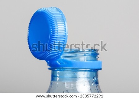 Close up of new cap attached to plastic bottle, connected to the neck of the bottle by solid tab attached to safety ring. They are intended to encourage recycling, as part of the fight against litter.
