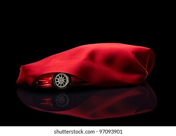 close up of  a new car hidden under red cover on black background
