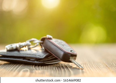 Close up new car keys with black leather wallet on wooden table. Car purchase or car rental concept
