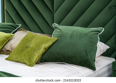 Close up of new green colored bed with decorative pillows, fabric headboard in bedroom in sample model of hotel or apartment