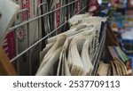 Close up of newspapers are stacked on rack, fresh editions and crosswords, folded in half.