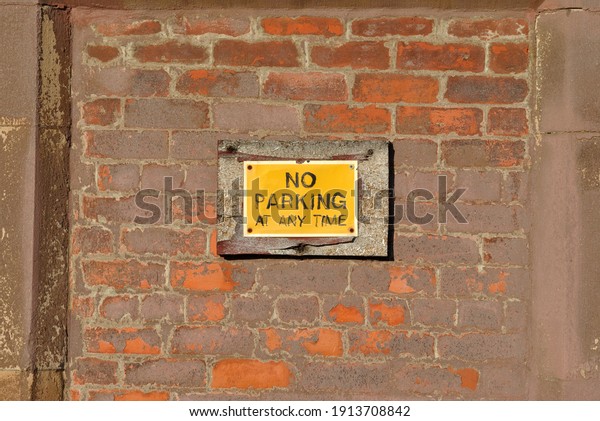 Close Up of\
\'No Parking\' Sign on Old Brick Wall\
