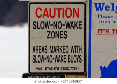 Close up of a No Wake Zone caution sign highlighting boating safety regulations and restricted speed area on a lake or waterway.