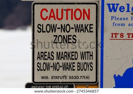 Close up of a No Wake Zone caution sign highlighting boating safety regulations and restricted speed area on a lake or waterway.