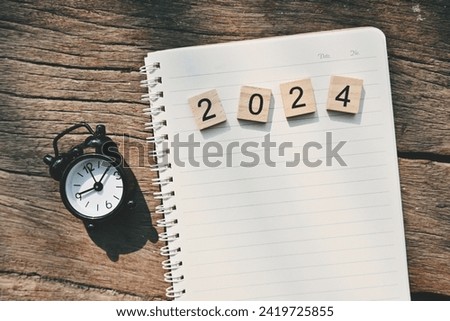 close up notebook, 2024 wooden text block and alarm clock on table, copy space for text, planning and manage to success business, to do list and mission goal wallpaper background concept