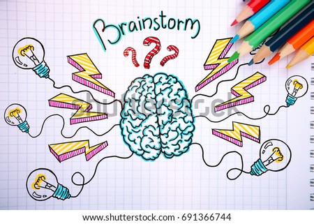 Close up of notepad with creative brainstorm sketch and colorful pencils. Brainstorming concept 