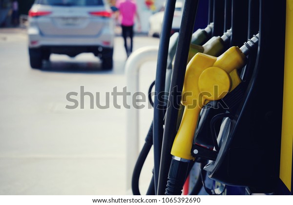 close up nozzle fuel for fill oil\
into car tank at pump gas station, saving money and energy for\
transport, transportation technology concept, vintage\
tone