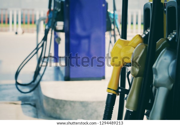 close up nozzle fuel for fill oil\
into car or motorcycle tank at pump gas station, transport energy,\
transportation power business technology concept, vintage\
tone