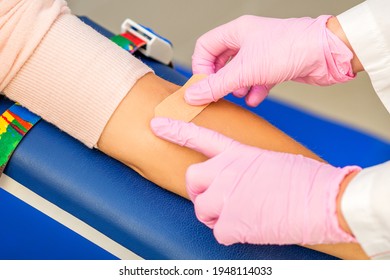 Close up of nurse hand applying adhesive plaster on arm of patient after blood collection in the hospital