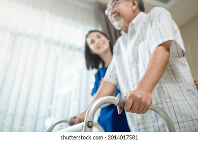 Close Up Of Nurse Help Disable Man Walk With Walker At Nursing Home. Caregiver Therapist Doctor Support Senior Older Handicapped Patient Use Zimmer Frame In House. Medical Therapy Insurance Concept.