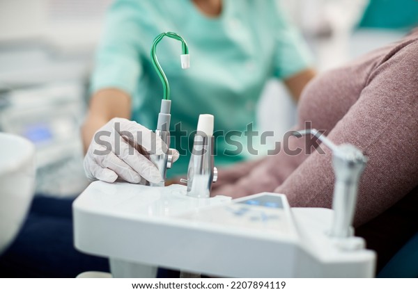 Close up of nurse using suction tube\
during patient\'s dental check up at dentist\'s\
office.