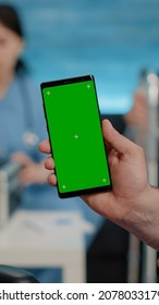 Close Up Of Nurse Vertically Showing Phone With Green Screen To Senior Patient Living In Nursing Home. Medical Specialist Holding Smartphone With Chroma Key And Isolated Mockup Template