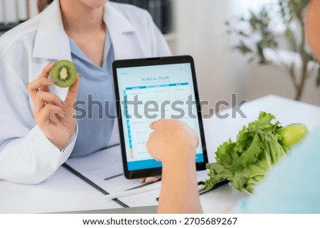 Close up nutritionist using tablet to explaining personalized meal plan with AI to patient during healthcare consultation, healthy lifestyle, woman dietitian showing nutrition plan with AI on tablet.