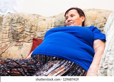 Close Up Of Obese Elderly Woman Relaxing On Sofa.