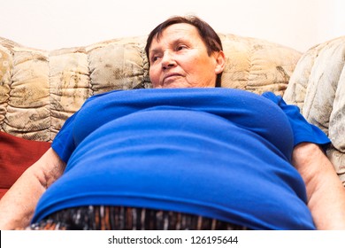 Close Up Of Obese Senior Woman Lying On Sofa.