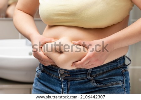 Close up of a obese young woman checking her fats in the bathroom