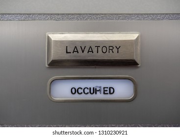 Close Up Of An Occupied Sign On An Aircraft Bathroom Door Indicating The Bathroom Is In Use. The Word 