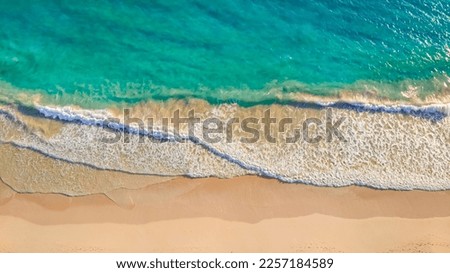 Close up of ocean waves rolling onto a beautiful beach with pink sand at sunrise. Sandy coastline with white turquiose sea waves. Soft wave of the sea on sandy beach with white clean foam