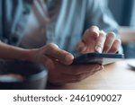 Close up of, woman sitting at wooden table using mobile phone in coffee shop, finger touching on phone screen. Woman using smartphone for mobile banking, online shopping, social media network