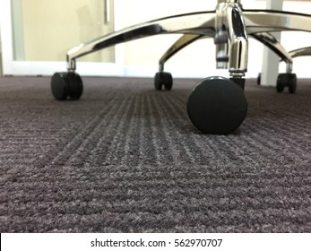Close Up Of Office Chair Wheels On Carpet.