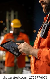 Close up of offshore platform engineer checking equipment status indicators on tablet system dashboard. Worker verifying hydraulic pressure levels on device digital monitoring panel app