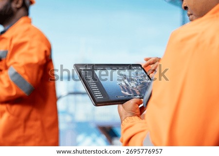 Close up of offshore platform experts using tablet app to monitor equipment performance in real time. Drilling rig colleagues working together to calibrate gear with asset management system on device