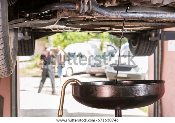 Close up of oil flows\
out into equipment for changing motor oil in automobile engine in a\
car workshop