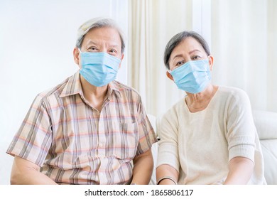 Close Up Of Old Couple Wearing Medical Mask To Prevention Coronavirus Spread While Sitting On The Couch. Shot At Home