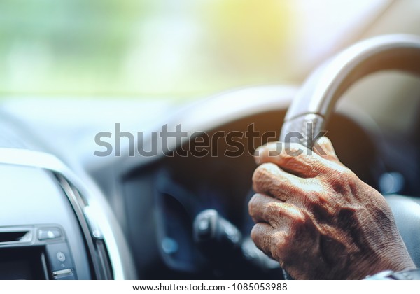 Close\
up old man driver keeps hands on the steering\
wheel
