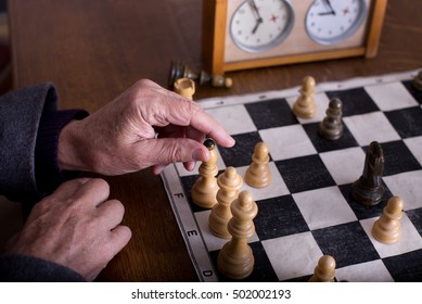 Close up of old man hands playing chess with wooden pieces