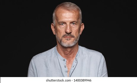 Close up of an old man looking at camera. Portrait of a senior man against black background. - Powered by Shutterstock