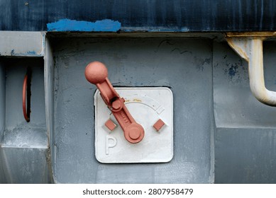 Close up of an old mechanical red control switch or parking brake lever with a letter P on a gray metal train surface.