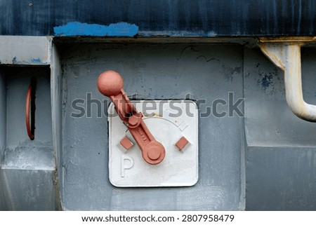 Close up of an old mechanical red control switch or parking brake lever with a letter P on a gray metal train surface.