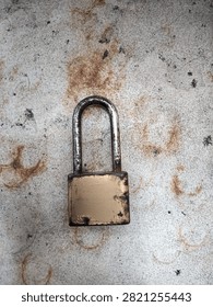Close up of an old rusty brass padlock on a weathered concrete ground 