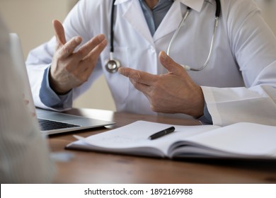 Close up old senior male general practitioner in white coat gesturing, explaining illness diagnosis or medical insurance benefits to patient at checkup meeting in clinic, medical communication concept - Shutterstock ID 1892169988