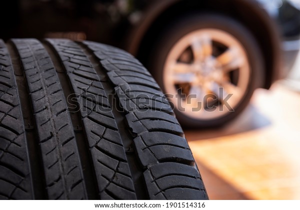 Close up of old tire with car\
wheel background. Tire workshop and change old wheel on the car.\
Used car tires stacked in piles at tire fitting service repair\
shop