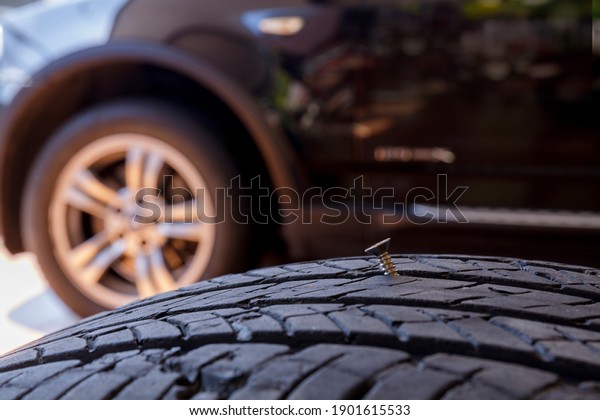 Close up old\
tire have nails nut or screw drive stuck in side. Tire workshop and\
change old wheel on the car. Used car tires stacked in piles at\
tire fitting service repair\
shop