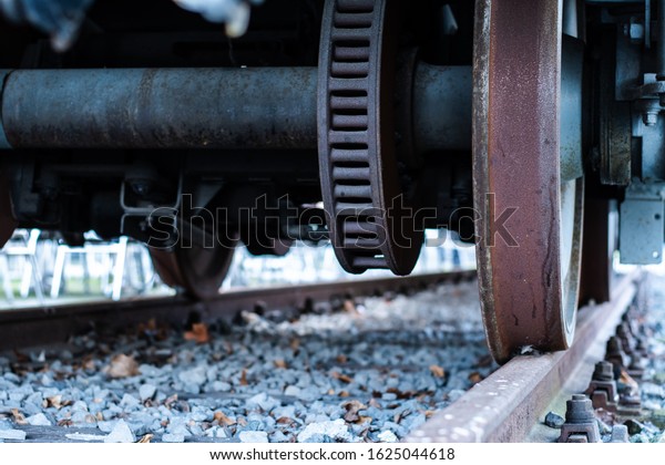Close up of an old train car undercarriage and\
its steel train wheels, rolling\
by