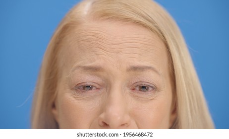 Close Up Old Woman Eyes In Front Of Blue Background Wink. Close Up Eyes Of The Concept.