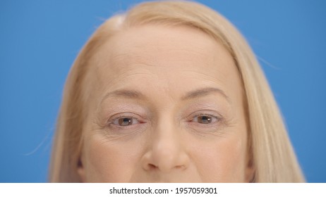 Close Up Old Woman Eyes In Front Of Blue Background Wink. Close Up Eyes Of The Concept.