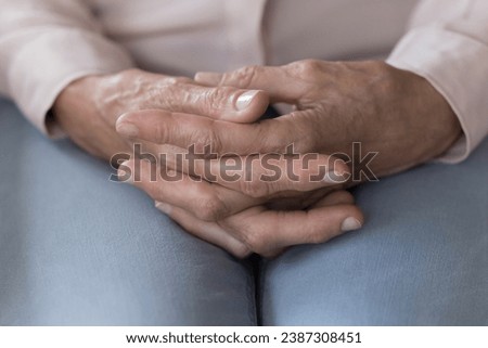 Close up of old woman hands folded on laps sitting indoors, feels lonely, desperate or anxious at nursing home, health problem, make difficult decision. Geriatric medicine, old person, mental disorder