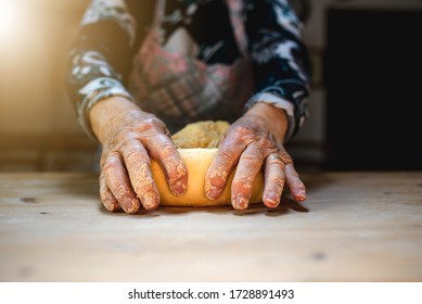 Close Up Old Woman Hands Kneading Dough To Prepare Fresh Italian Pasta Homemade On A Wooden Cutting Board.