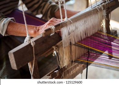 Close up of old woman weaving blue and white pattern on loom