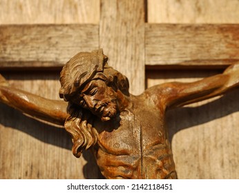 Close up of an old wooden crucifix, face of Jesus Christ on wooden cross in sunlight
