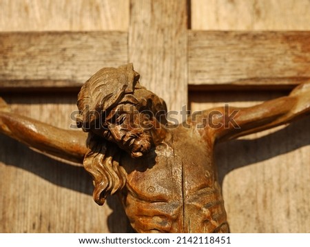 Close up of an old wooden crucifix, face of Jesus Christ on wooden cross in sunlight