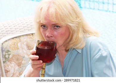 Close Up Of An Older Woman Drinking Wine Near The Swimming Pool.