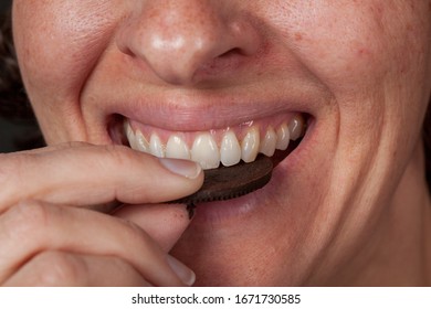 Close Up Of Older Woman Eating A Chocolate Cream Filled Cookie. Unhelathy Lifestyle Junk Food Concept.